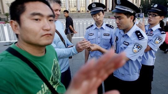 Beschreibung: Ein Polizist in Zivil behindert einen Fotografen in Peking.